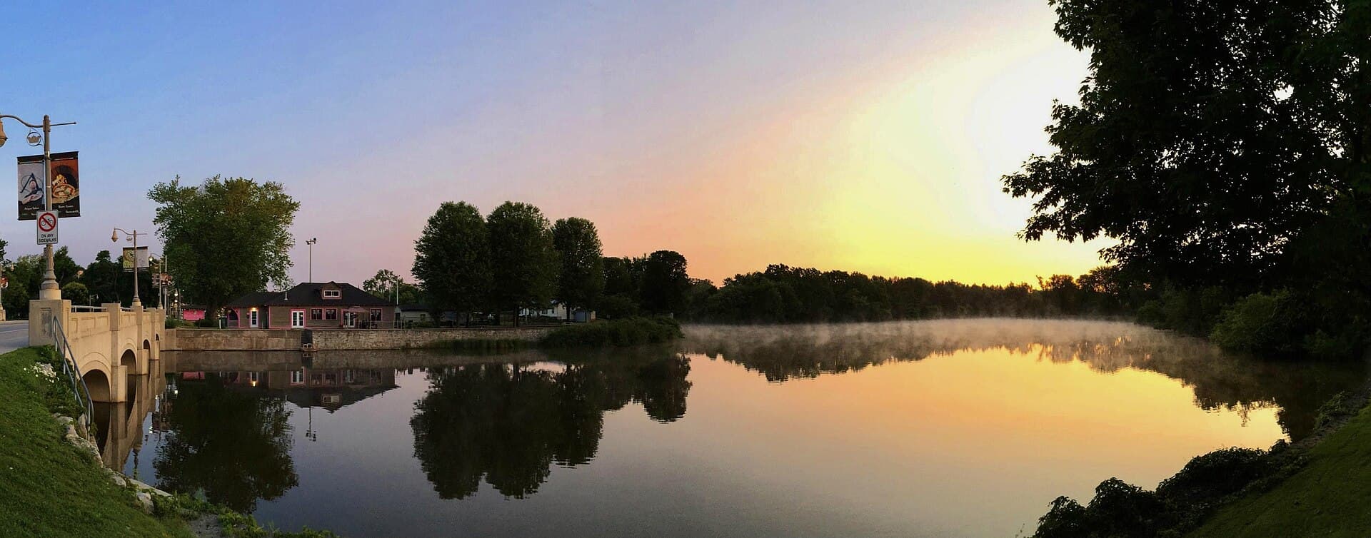 Morning mist on the Speed River in Guelph at sunrise, with the stone bridge reflected in still water